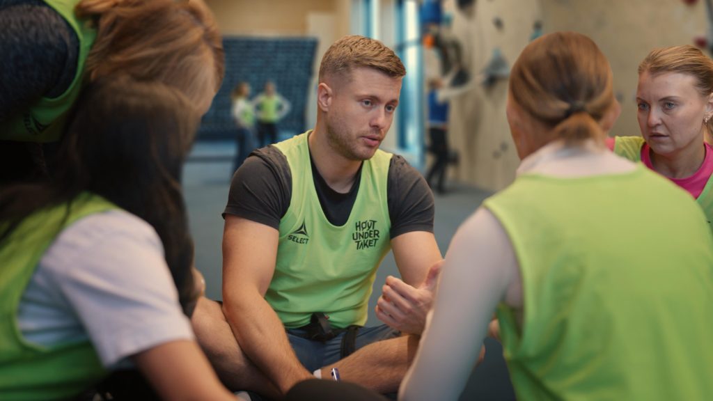 Ansatte i teambuilding-samling diskuterer erfaringer i klatrehall hos Høyt Under Taket